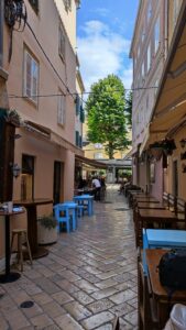 Outdoor café terrace with blue stools and wooden tables on a Split old town cobblestone alley