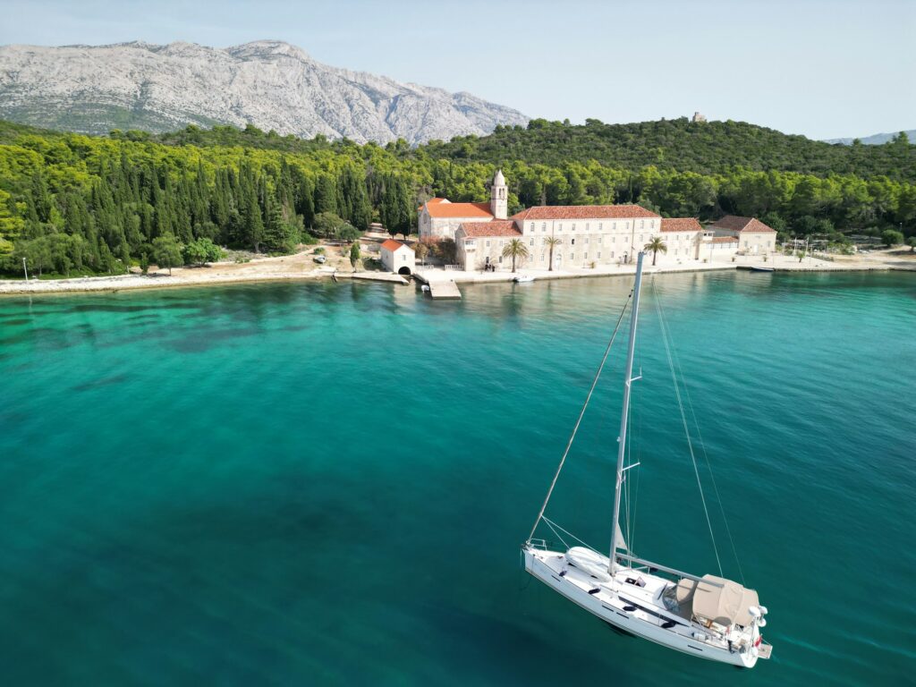A sailboat on turquoise Adriatic water by a Dalmatian stone island — island-hopping by boat from Split