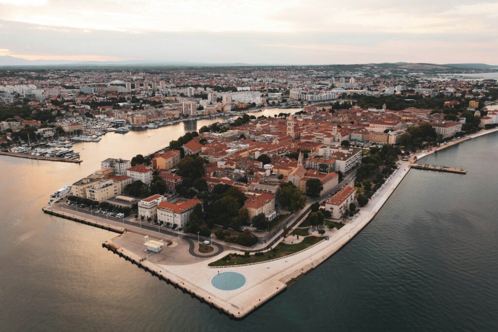 Aerial view of Zadar's historic peninsula at golden hour, with the Greeting to the Sun and Sea Organ at the tip