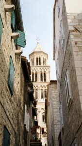 A narrow stone lane in Split's old town framing the Romanesque bell tower of St Domnius