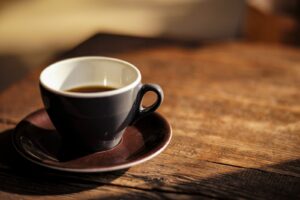 An espresso cup on a worn wooden table in warm light