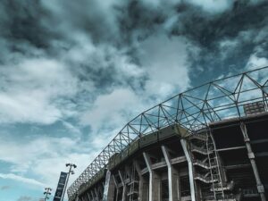 A low angle on a concrete and steel stadium stand against a dark dramatic sky